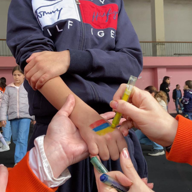 Volunteers drawing an Armenian flag on a child